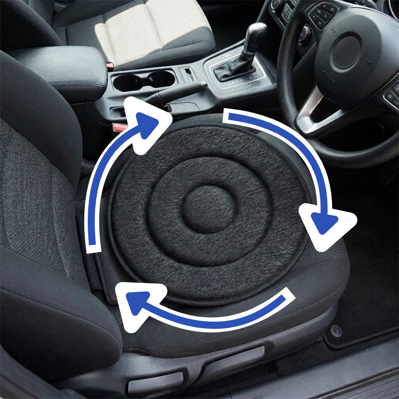 A circular black car seat cushion placed on a front passenger seat inside a vehicle, with blue arrows overlaid to suggest rotation. The image shows the car interior, including the steering wheel, gear shift, and adjacent seat.