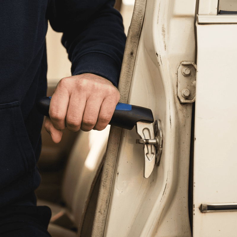 A close-up of a person's hand holding Handly, a black and blue car door assist handle for support.