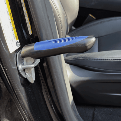 A close-up of a car door assist handle clipped into the car's door striker, gray leather car seat.